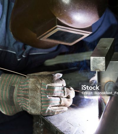 professional welder welding metal parts in steel construction company